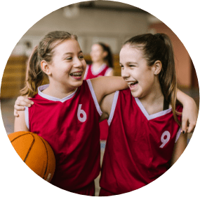 Two young girls in basketball uniforms smiling