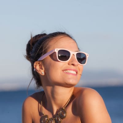 Woman at the beach smiling and wearing sunglasses