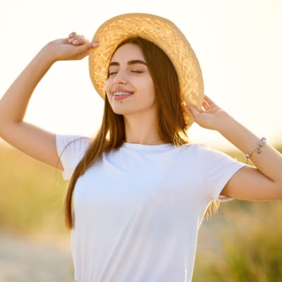 woman outdoors wearing a straw hat smiling