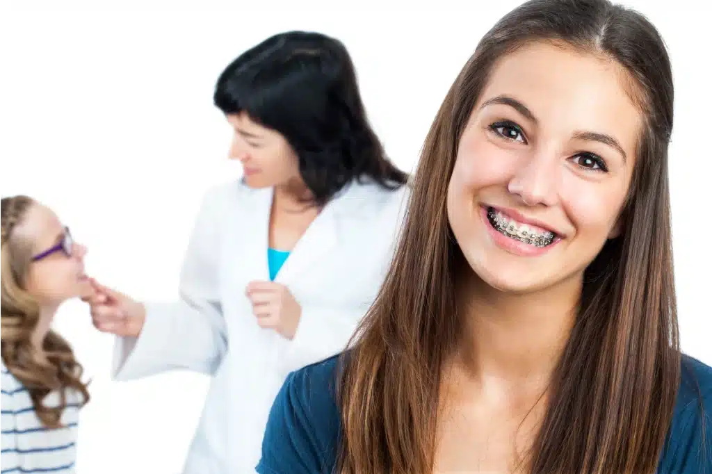 Teen girl with dental braces and doctor with patient in background