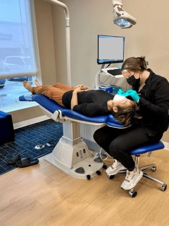 Dental assistant treating a patient in the chair at Smiles By Design